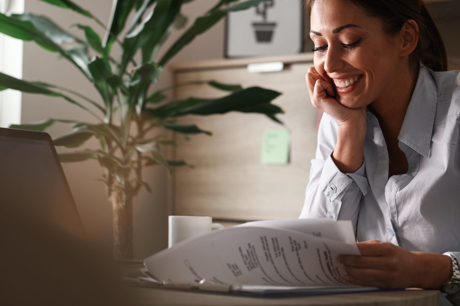 Young happy businesswoman reading reports while working in the o